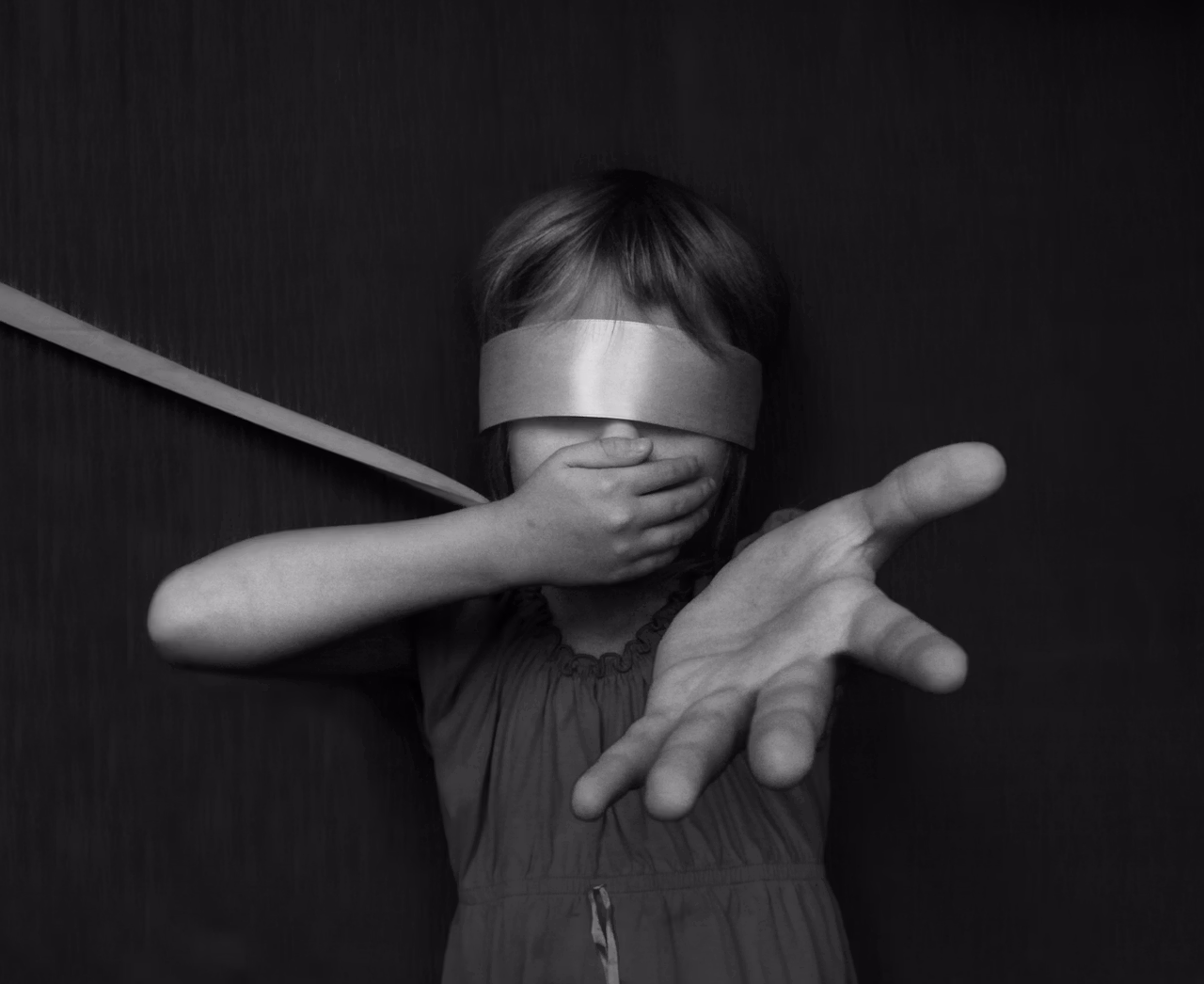 Niño con los ojos cubiertos por las manos de un adulto, símbolo de la interferencia parental